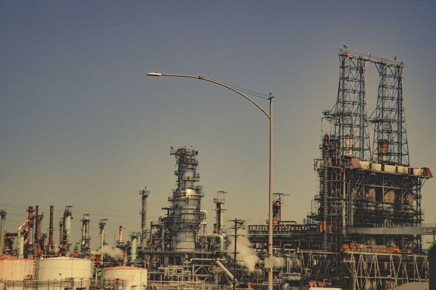 Towers and piping of an industrial process plant against an evening sky.